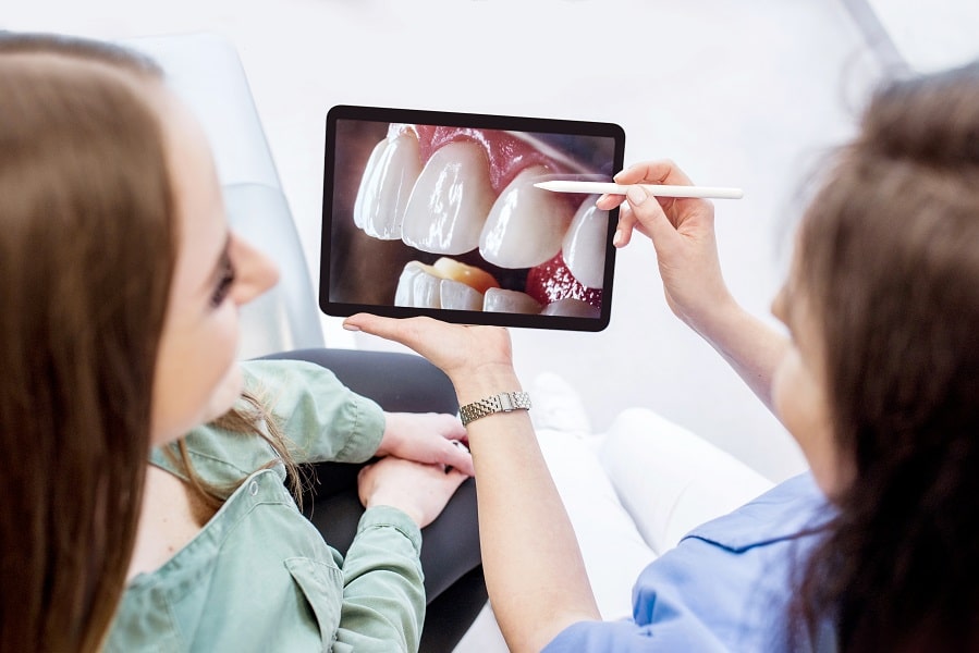 Omawianie przez dentystę projektu przyszłego uśmiechu na tablecie